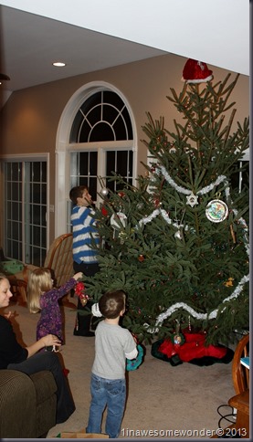 The family is involved, decorating this monster tree.